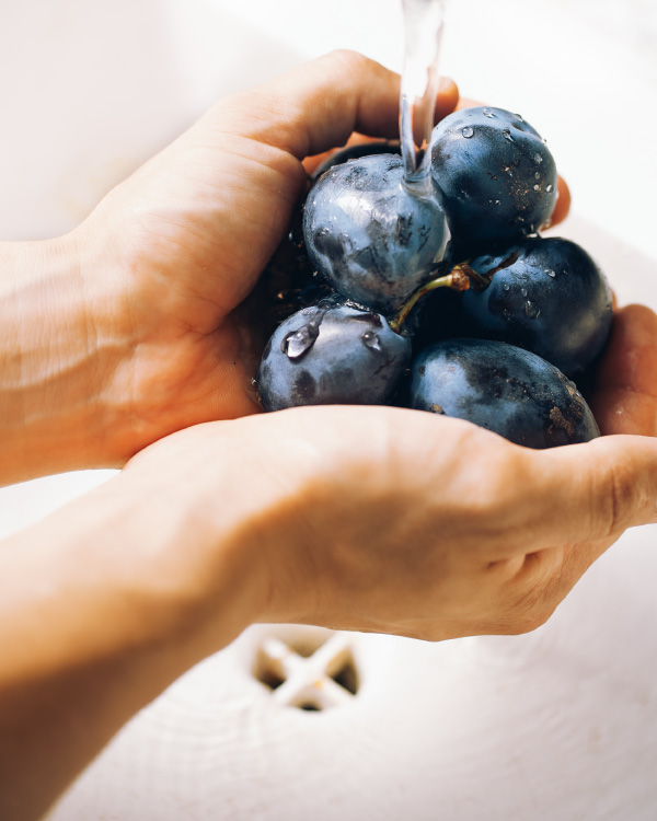 cleaning plums under a faucet